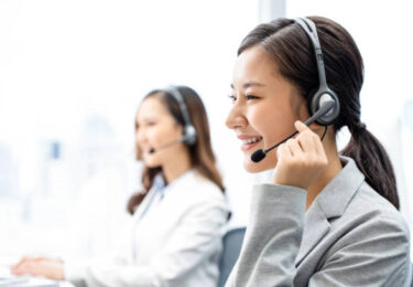 Smiling telemarketing Asian woman working in call center office